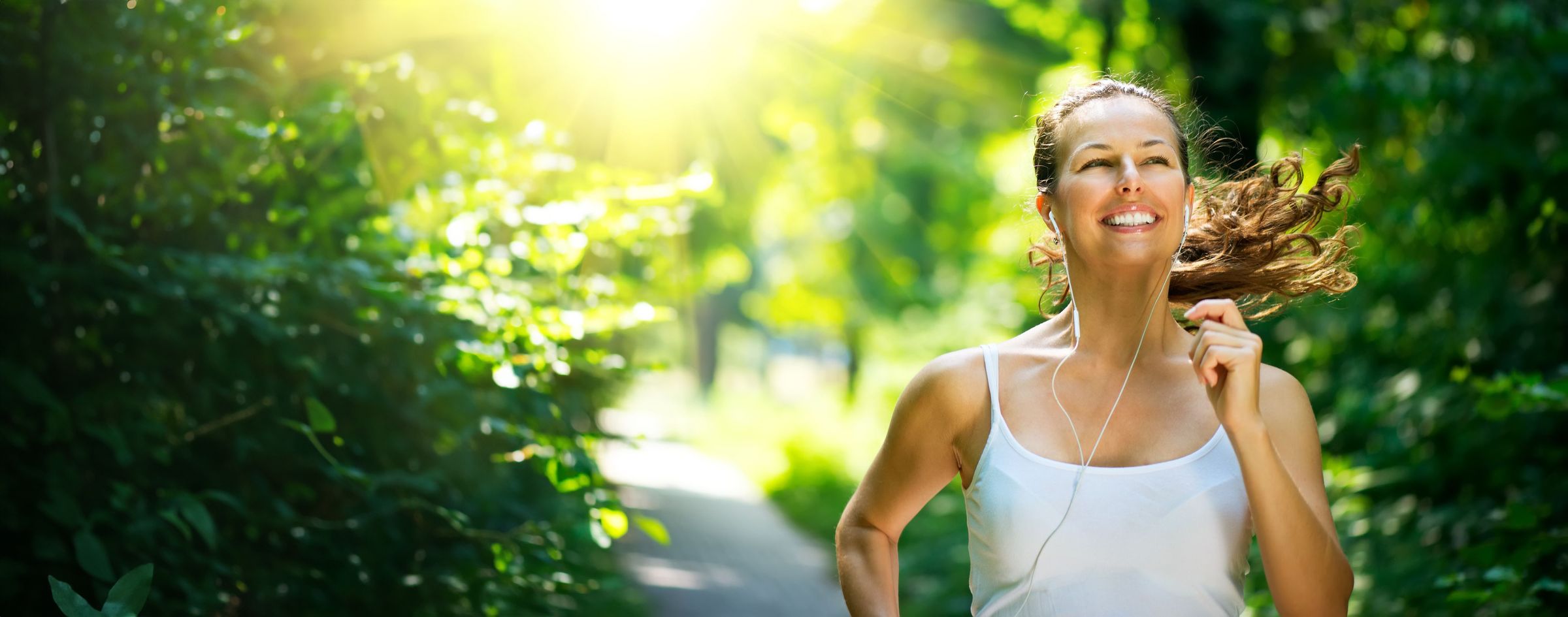 Donna sorridente che corre immersa nel verde: il benessere naturale che GinPent aiuta a sostenere ogni giorno